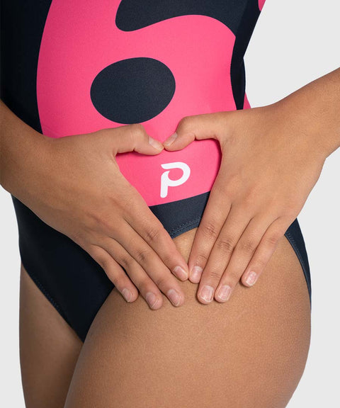 Person wearing a black training leotard with a pink and black logo, holding hands in a heart shape.
