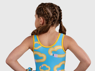 Gymnast wearing the Plum ABC Unitard, a sky-blue leotard with a fun pencil and cloud design, featuring a comfortable full-length fit.