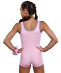 Gymnast wearing the Plum Bowtastic Unitard in soft pastel pink with an embroidered bow and matching scrunchie.