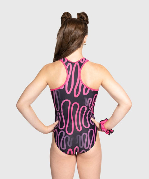 Person wearing a black leotard with pink and purple pattern on a white background