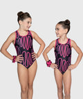 Two young girls wearing matching pink and black leotards on a plain background