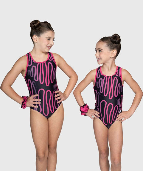 Two young girls wearing matching pink and black leotards on a plain background