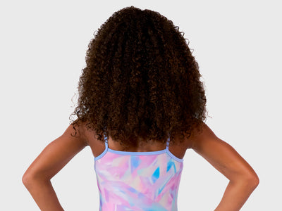 The Plum Ice Prism Leotard features pastel shades of pink, white, grey, and purple with spaghetti straps for freedom of movement. Made from breathable fabrics and smooth seams. Includes a matching scrunchie. 