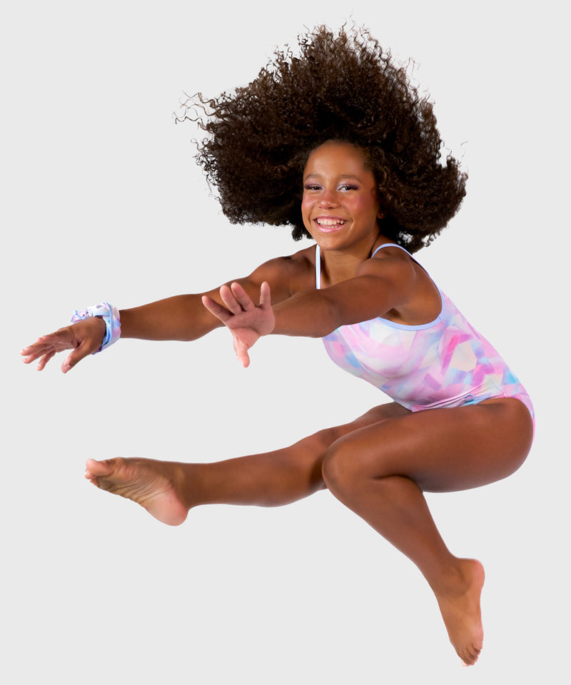 The Plum Ice Prism Leotard features pastel shades of pink, white, grey, and purple with spaghetti straps for freedom of movement. Made from breathable fabrics and smooth seams. Includes a matching scrunchie. 