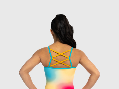 Girls coral shimmer leotard with criss-cross straps. Bold and radiant gymnastics tank.
