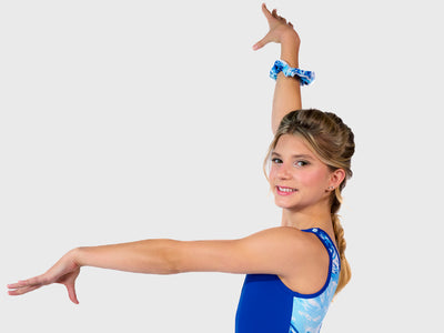 Plum Snowbound Flipside Leotard with solid blue front and swirly blue-and-white back. Designed for gymnasts with smooth seams and a matching scrunchie. 