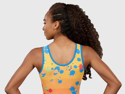 Gymnast wearing the Plum Splat Spaghetti Strap Leotard with a bold red front and a colorful ombré paint-splatter back. 