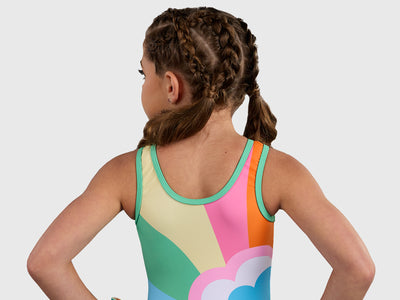 Gymnast wearing the Plum Sprinkles Unitard, a colorful retro gymnastics unitard with a bold rainbow and flower design. 