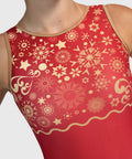 A close-up of a red sleeveless gymnastics leotard featuring a gold snowflake and star pattern across the upper chest and shoulders, with a scalloped gold border near the waistband.
