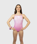 A young female swimmer modeling a pink one-piece swimsuit with delicate white floral embroidery on the chest, set against a solid light gray background.